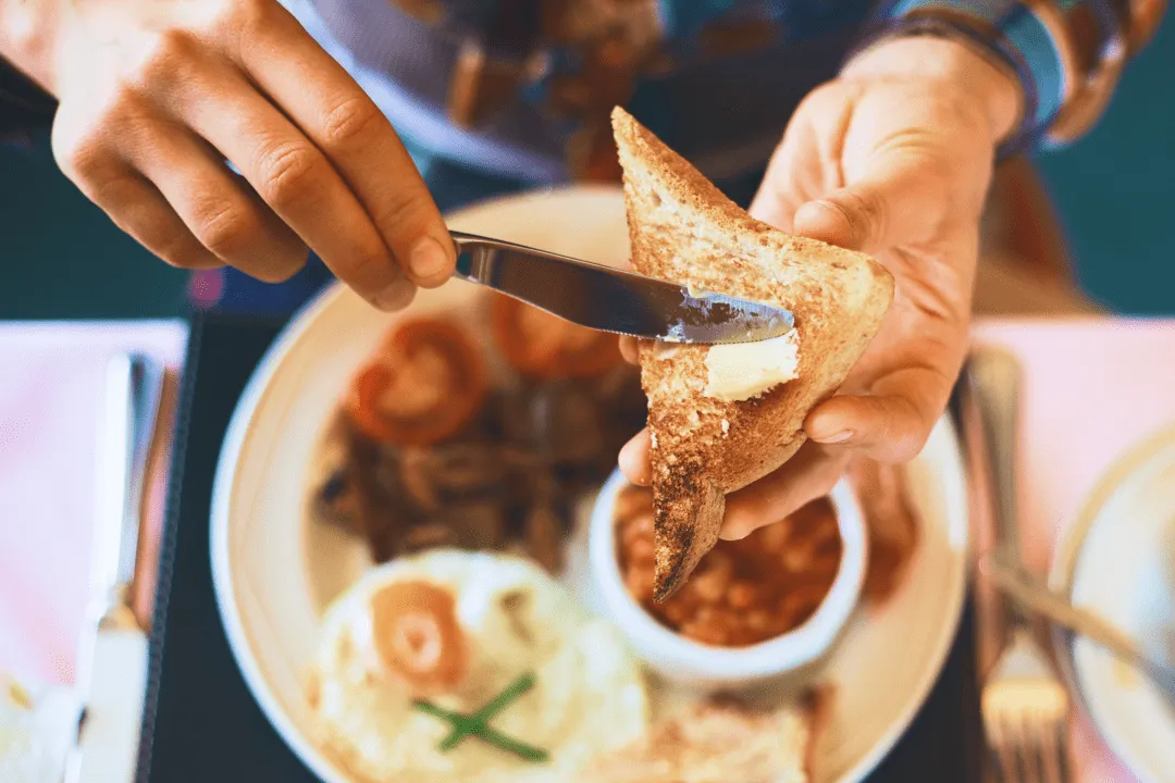 Мужчина намазывает масло на хлеб