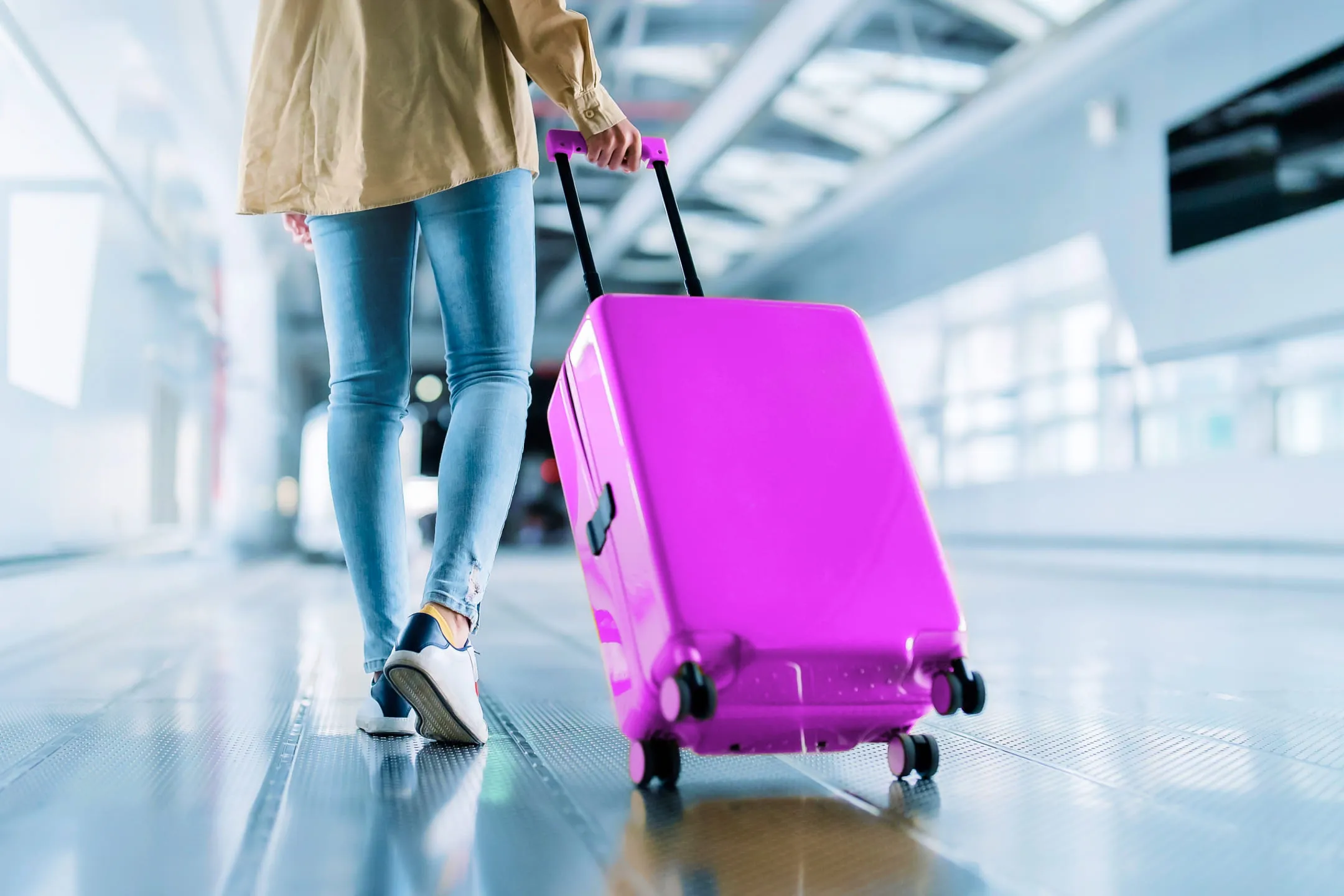 Девушка катит чемодан на колесиках
