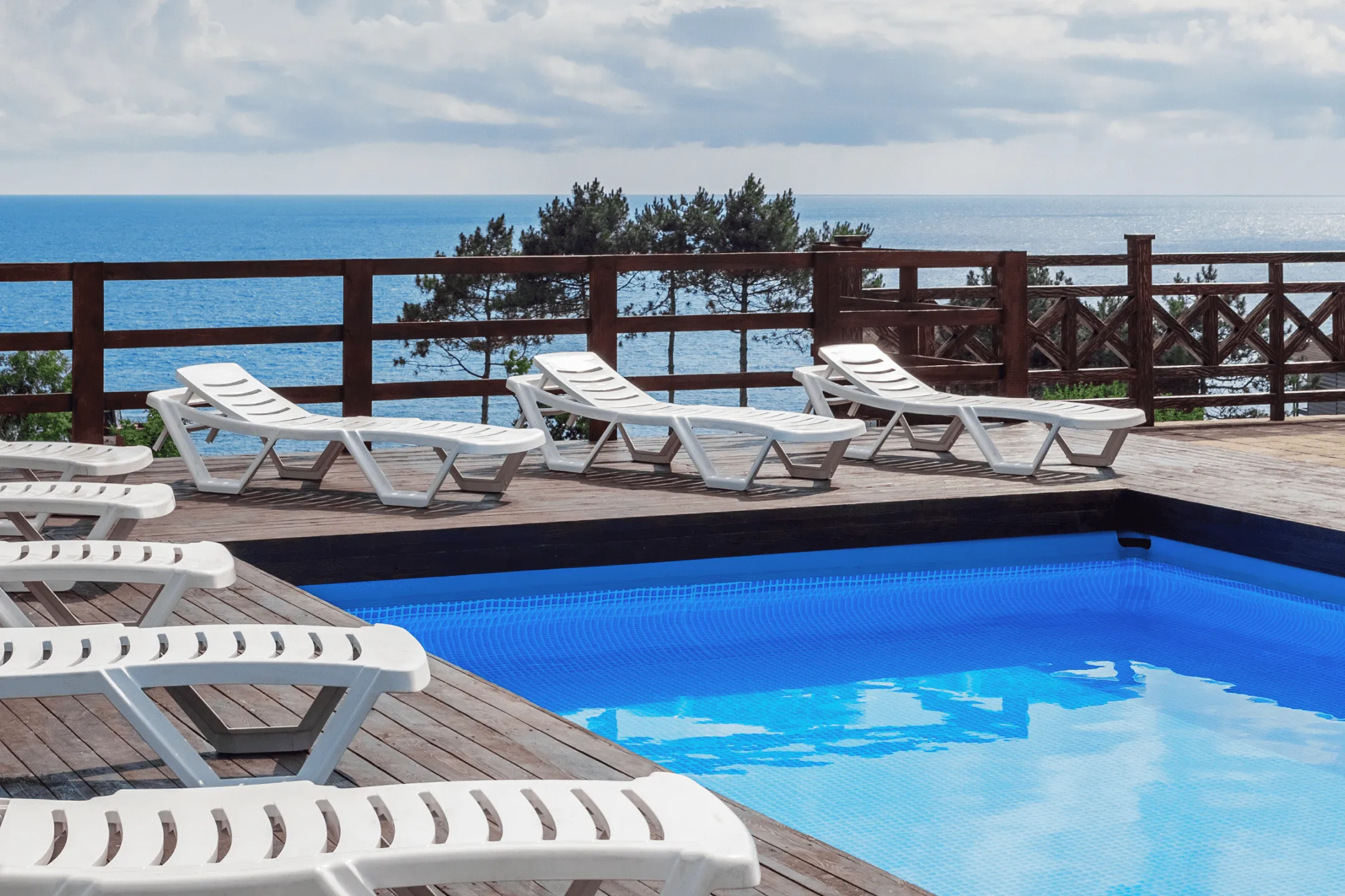 Белые шезлонги на краю бассейна