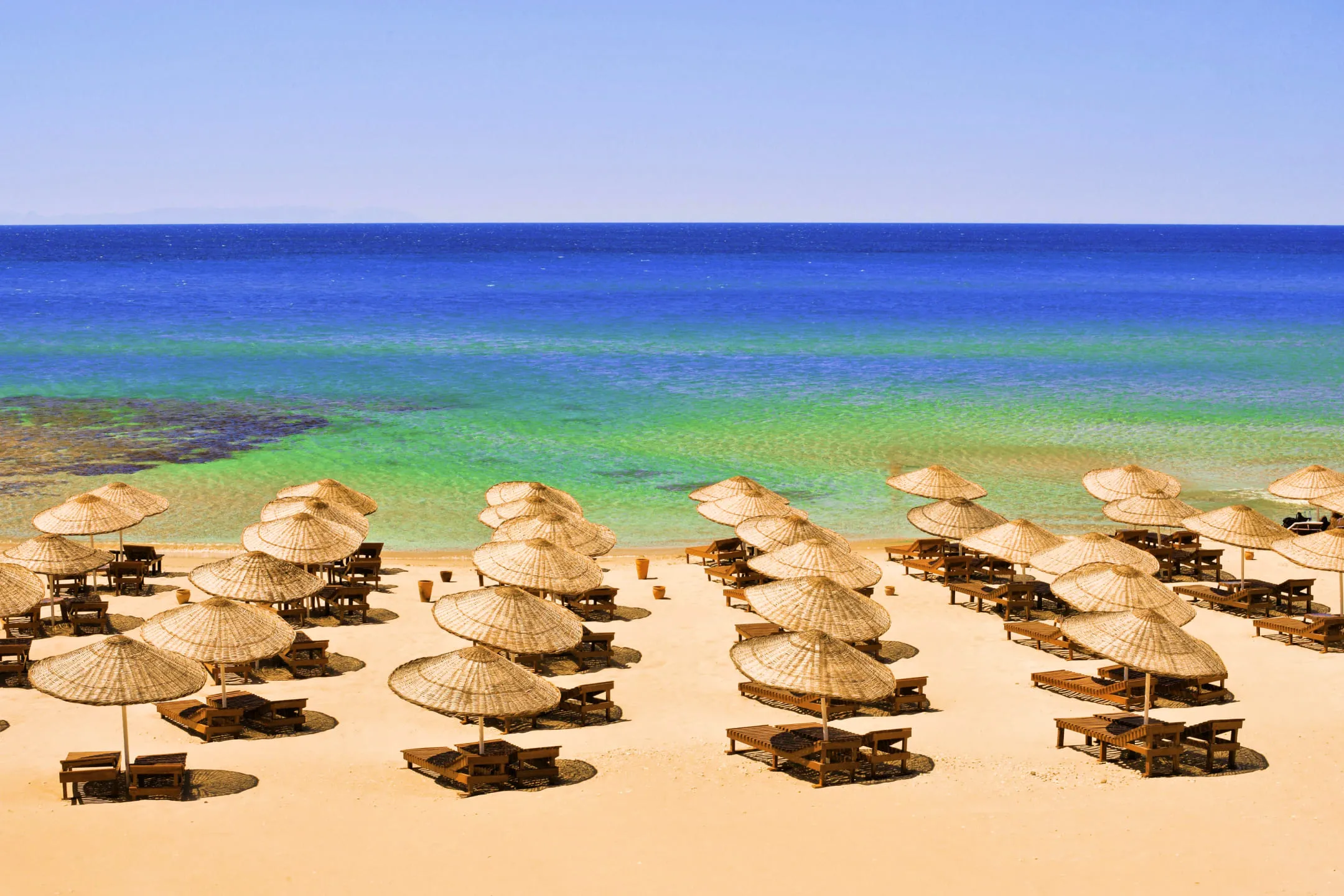 Шезлонги с пляжными зонтиками около моря