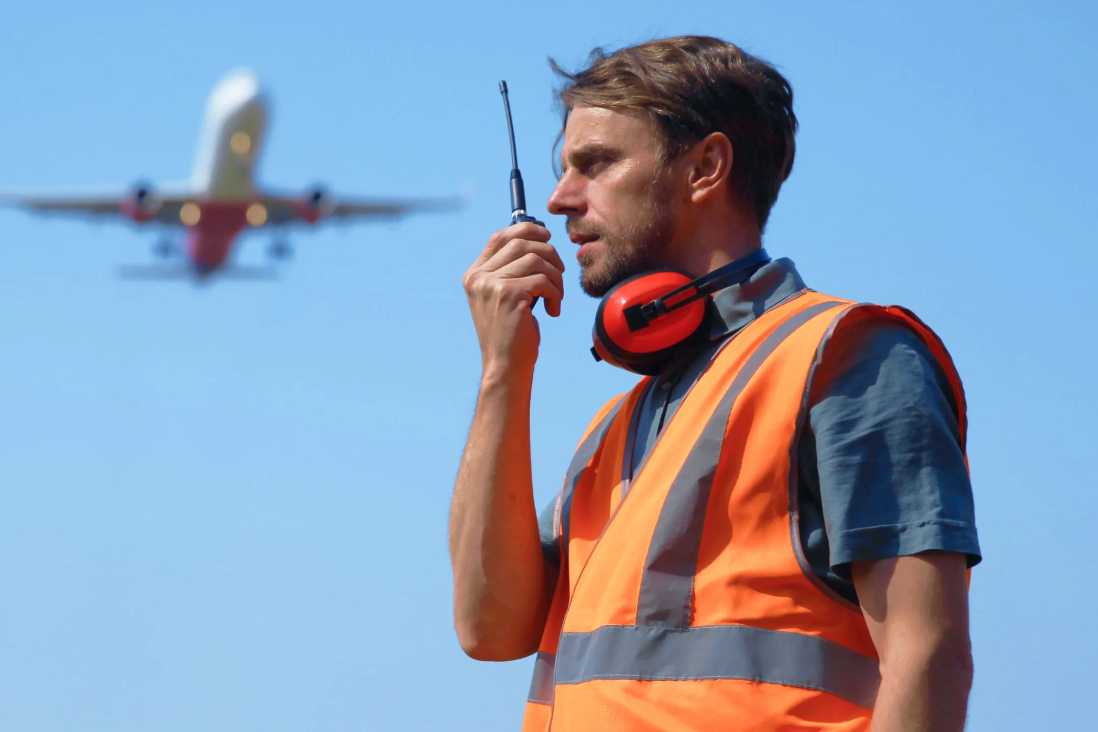 Человек в оранжевой жилетке общается по рации