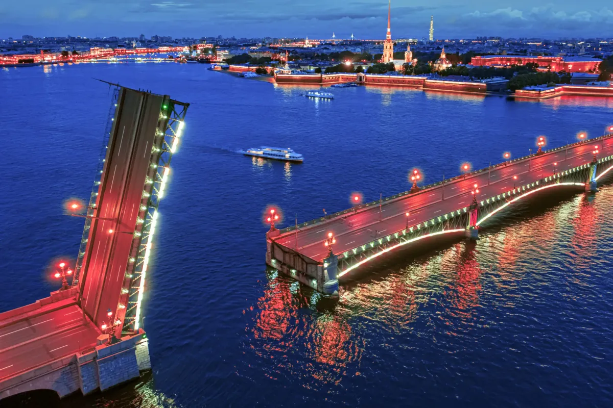 Небольшая яхта проплывает около разведенных мостов