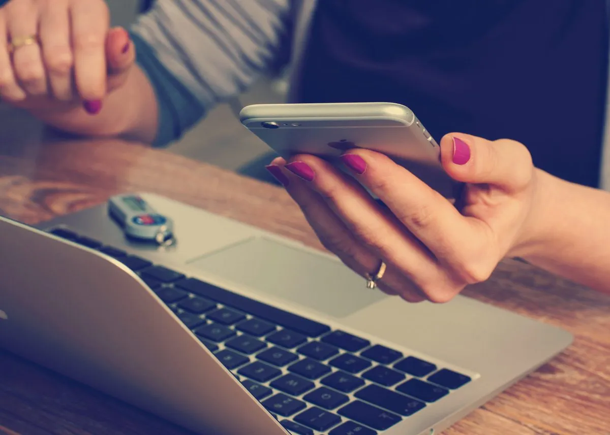 Девушка сверяет информацию на телефоне и ноутбуке