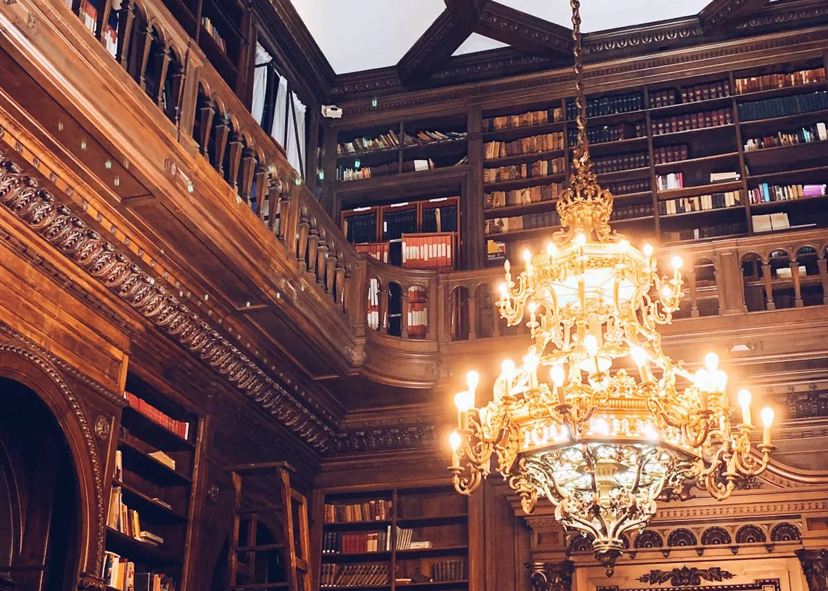 Большая люстра свисает с потолка библиотеки