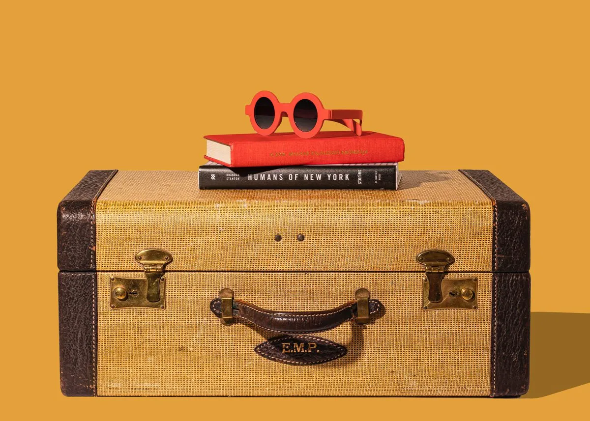 Книги с солнцезащитными очками на чемодане