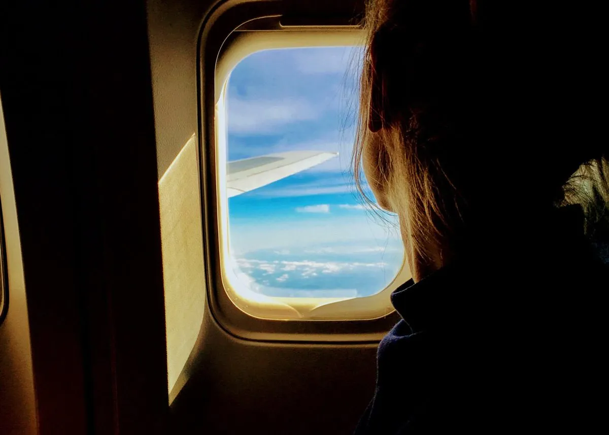 Девушка смотрит в иллюминатор самолёта