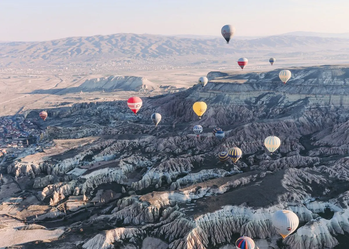 Воздушные шары поднимаются над скалами в Каппадокии