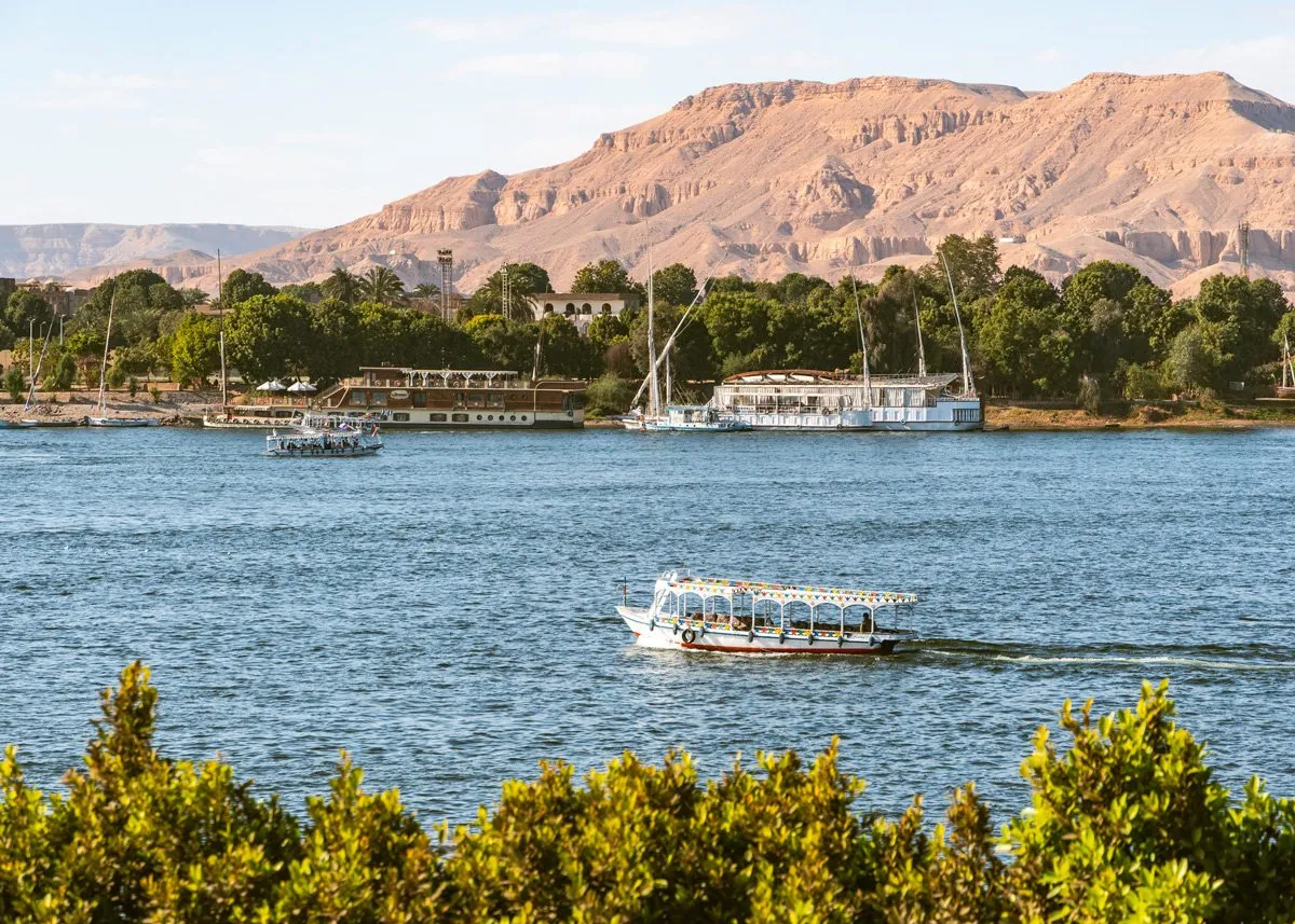 Лодка с людьми проплывает мимо горных хребтов