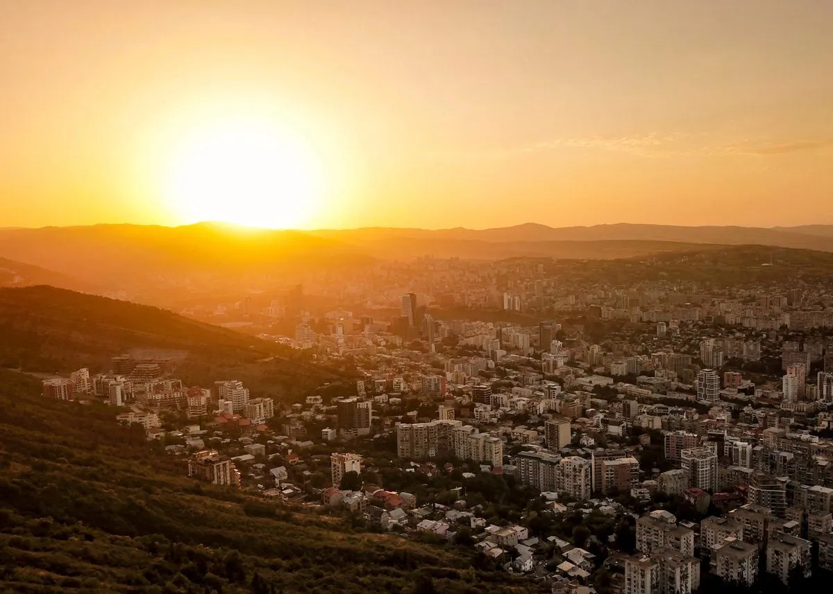 Многоэтажные здания освещает закатное солнце