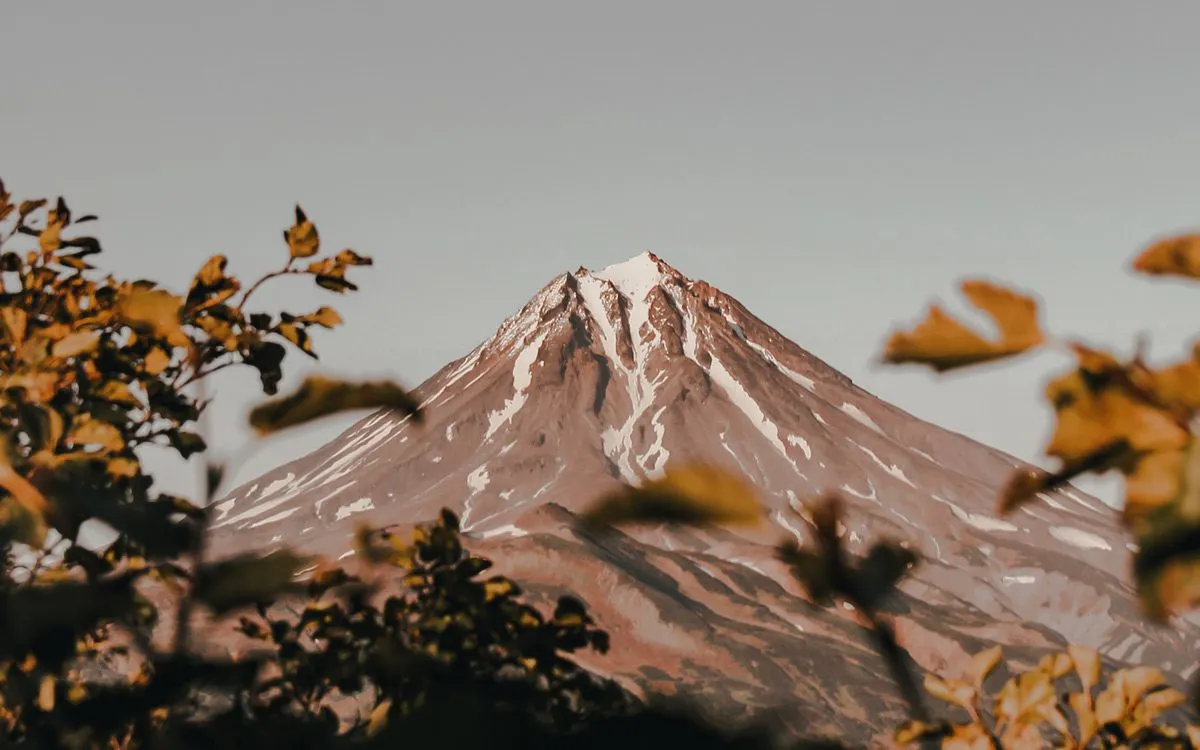 Виднеющаяся верхушка вулкана среди деревьев