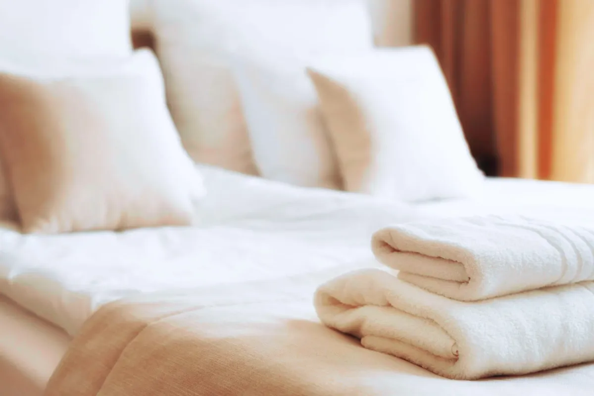 Белые полотенца сложены на белой кровати